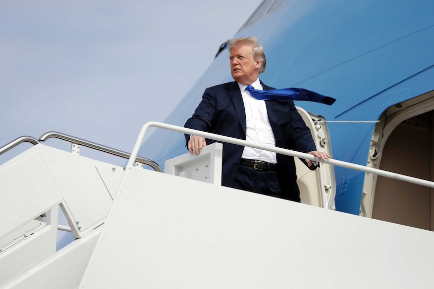 President Donald Trump looks out from Air Force One with his blue tie flittering in the wind.
