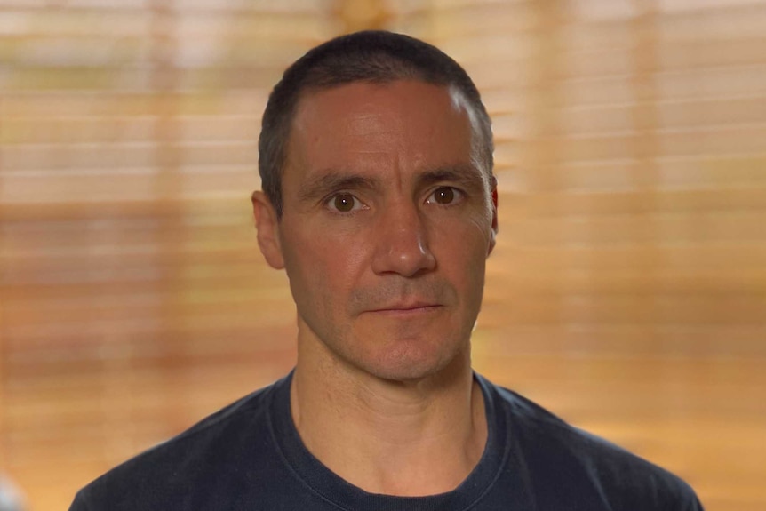 A portrait of a young man in a t-shirt in a room.