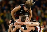 Sam Draper's hair is flying as he jumps on top of a pack of Essendon teammates