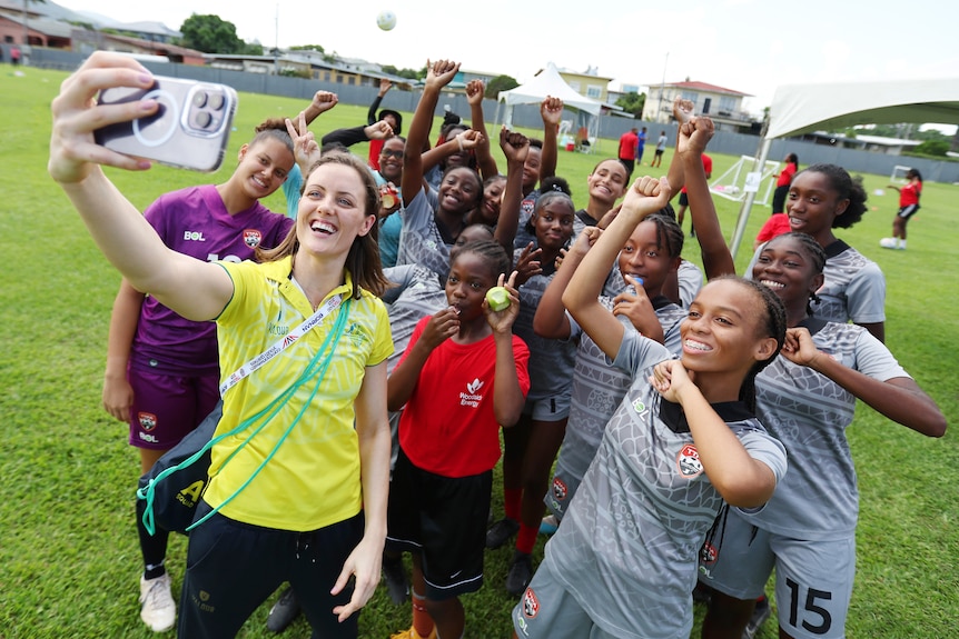 A smiling Ellie Cole poses for a selfie with young athletes.