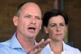 Campbell Newman holds hand up with Deb Frecklington listening beside him.