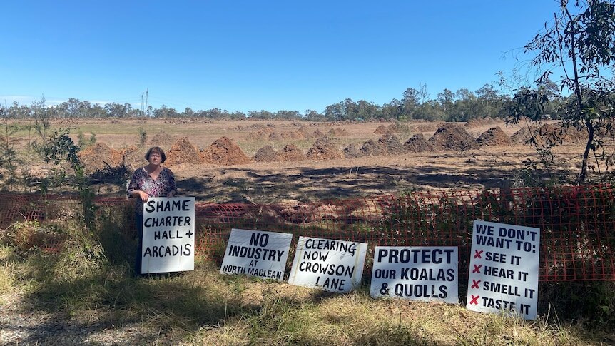 A woman stands with anti-land clearing signs.