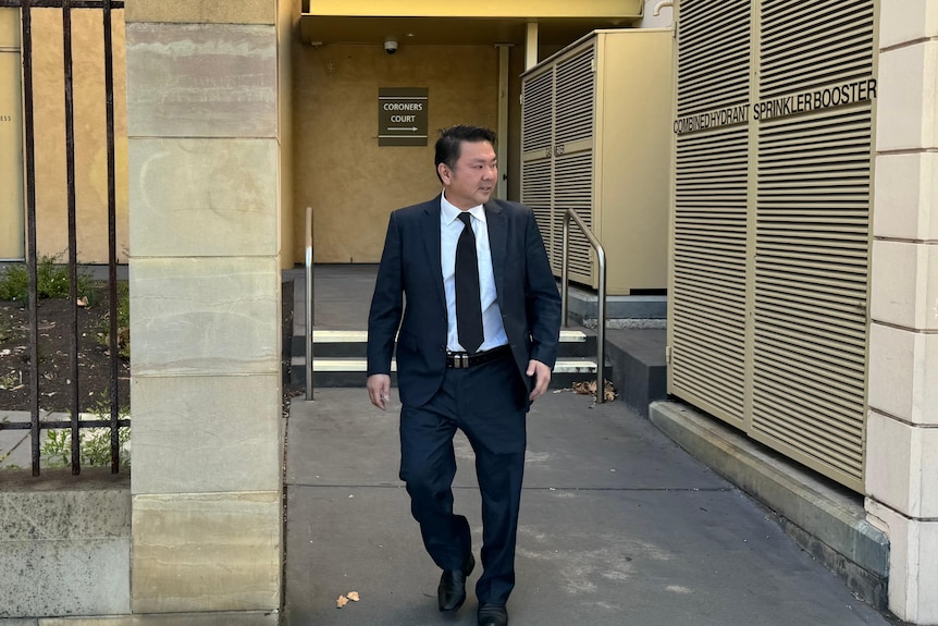 A man in a suit and tie leaves the SA Coroners Court.