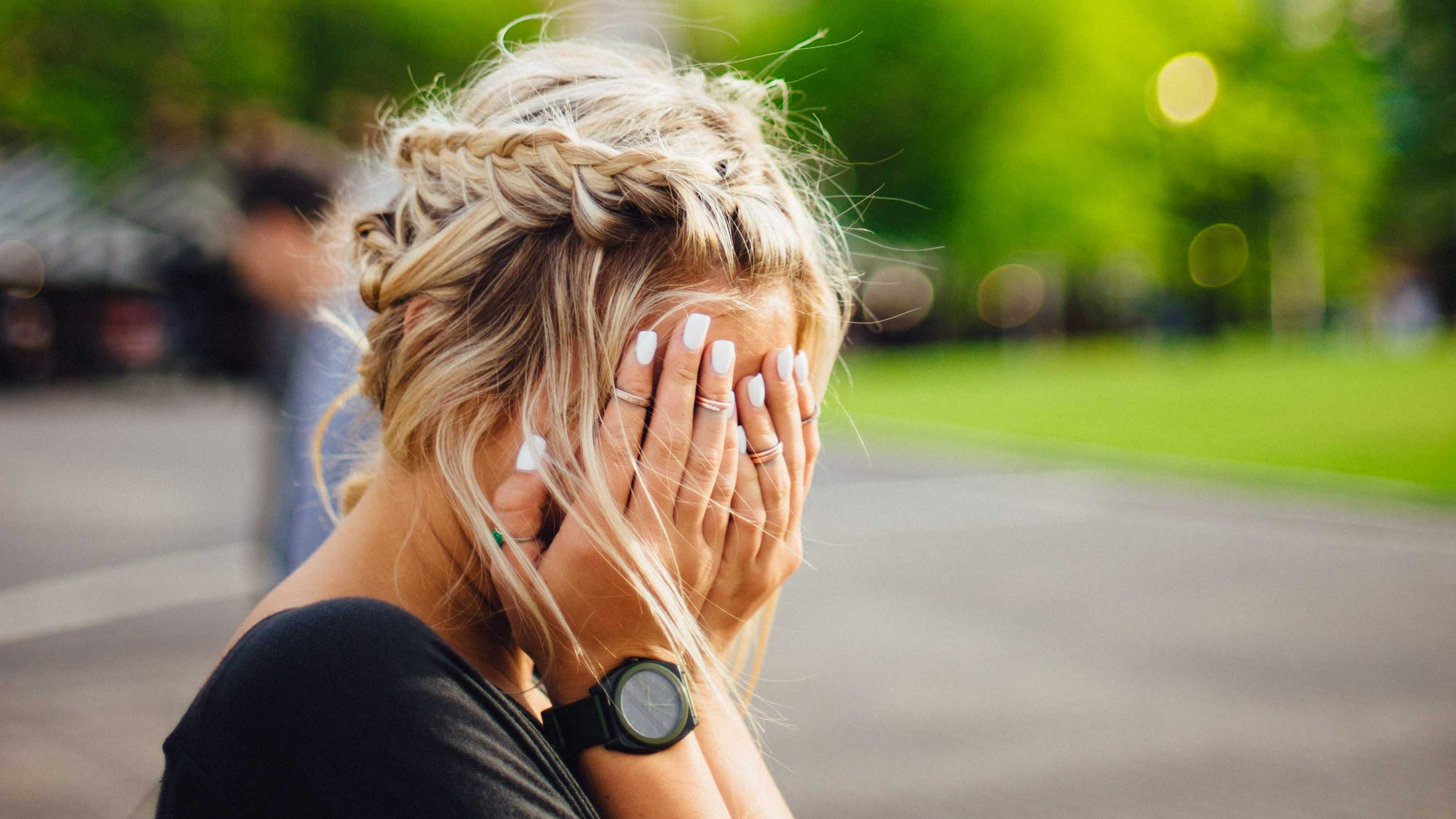 A woman covers her face with her hands, for a story about work rights and the JobKeeper scheme.