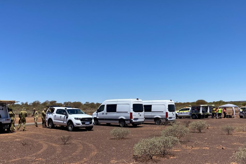 Several white vehicles parked off road. 