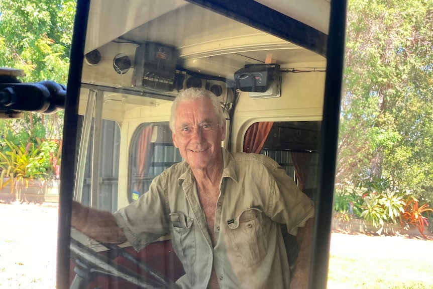 a photo of a man behind the driving wheel, reflected in the side mirror