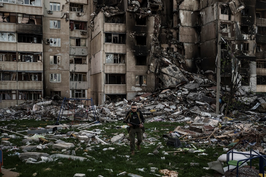 A Ukrainian serviceman walks amid the rubble of a heavily damaged building.