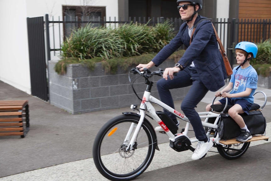 A commuter and child ride an electric cycle