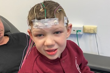 Seven year old boy with wires taped to head. 