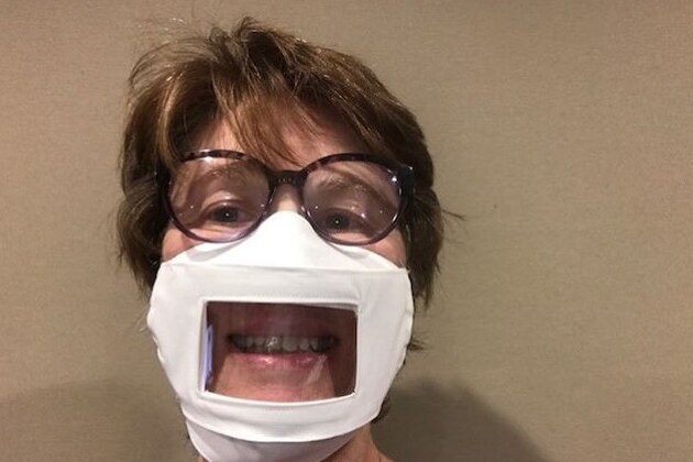 Tracey Nuthall smiles at the camera, wearing a face mask with a plastic window covering part of her face