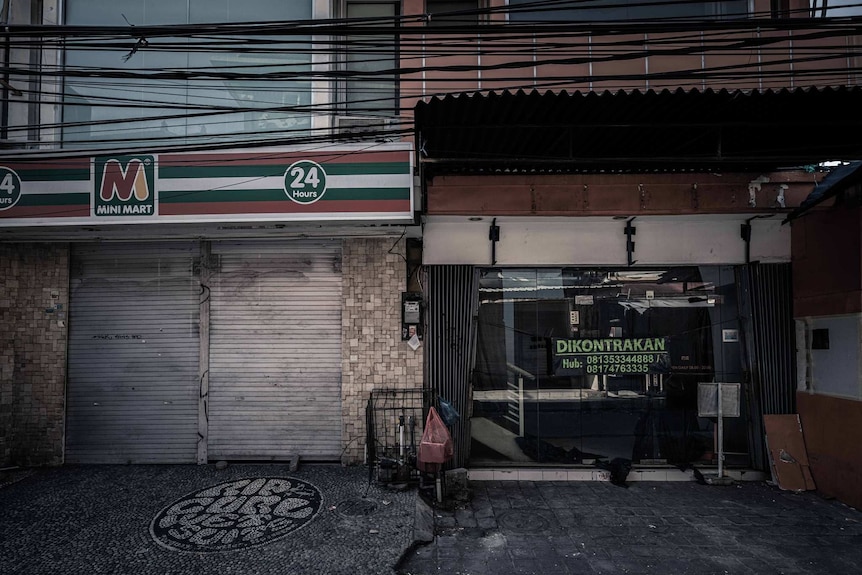 Closed shopfronts in Kuta, Bali, with one up for lease.