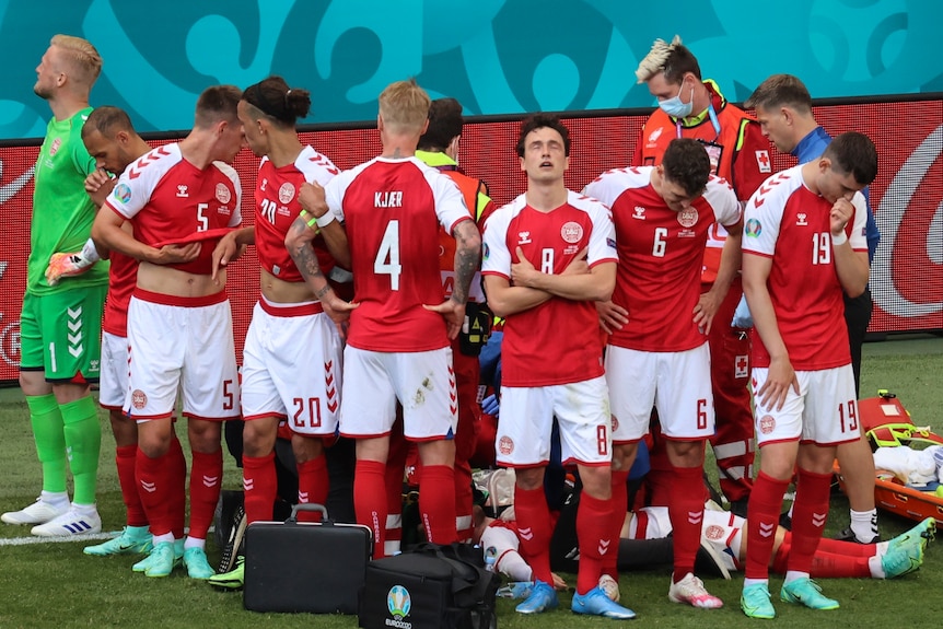 Denmark players show emotion as they form a barrier around Christian Eriksen