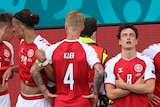 Denmark players show emotion as they form a barrier around Christian Eriksen