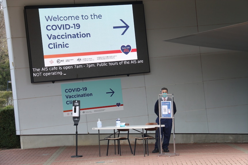 A security guard stands in front of a sign at the mass vaccination hub 