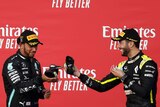 Lewis Hamilton (left) and Daniel Ricciardo hold their race boots out to each other as if to toast before drinking from them