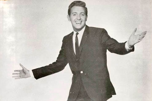 A black and white publicity shot of Jimmy Hanna dressed in a suit and tie