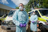 Emma Johnson and Steven Schrieke, from St John Ambulance (NT), are wearing full PPE and standing in front of an ambulance.