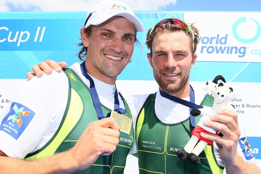 Alex Hill (left) and Josh Booth (right) hold up their Olympic gold medal.