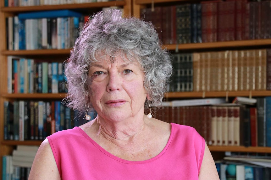 Beth Muller sitting in front of a book shelf.