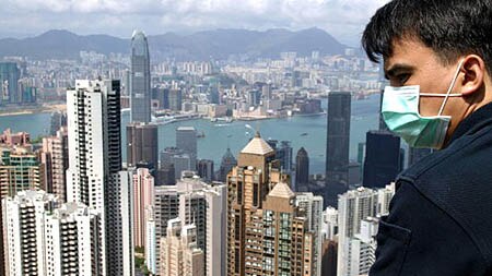 A tourist looks out over Hong Kong harbour whilst wearing a mask to protect himself from SARS