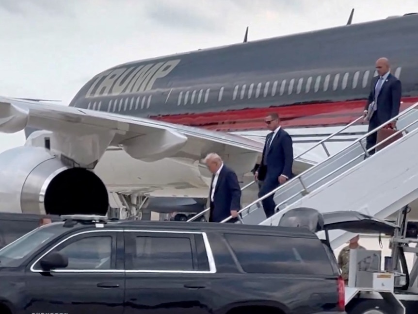 Donald Trump walks down stairs at the back of his plane.