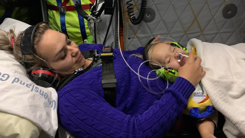 A woman holds her child who is hooked up to an oxygen mask