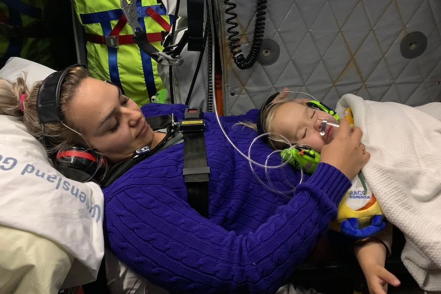 A woman holds her child who is hooked up to an oxygen mask