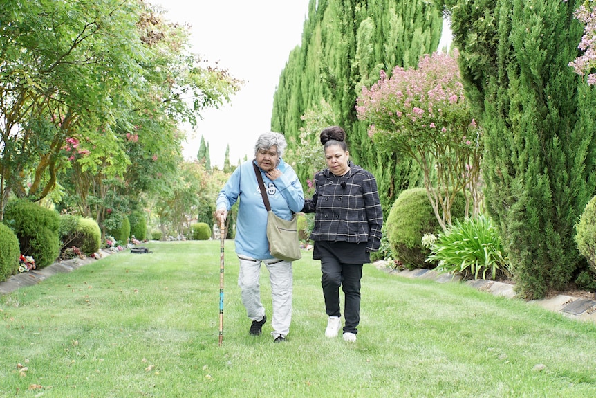 Diana Nikkelson and her daughter Nikki Foy walk together on a green lawn.