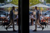 A man walks past cafes and restaurants on a street in Canberra.