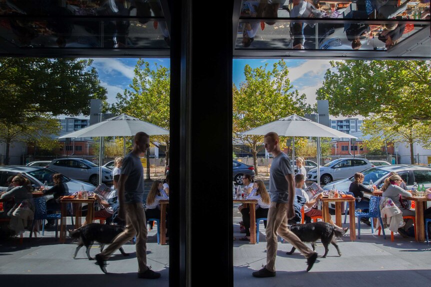 A man walks past cafes and restaurants on a street in Canberra.