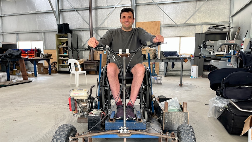 A man in a wheelchair on a vehicle that resembles a go-kart.