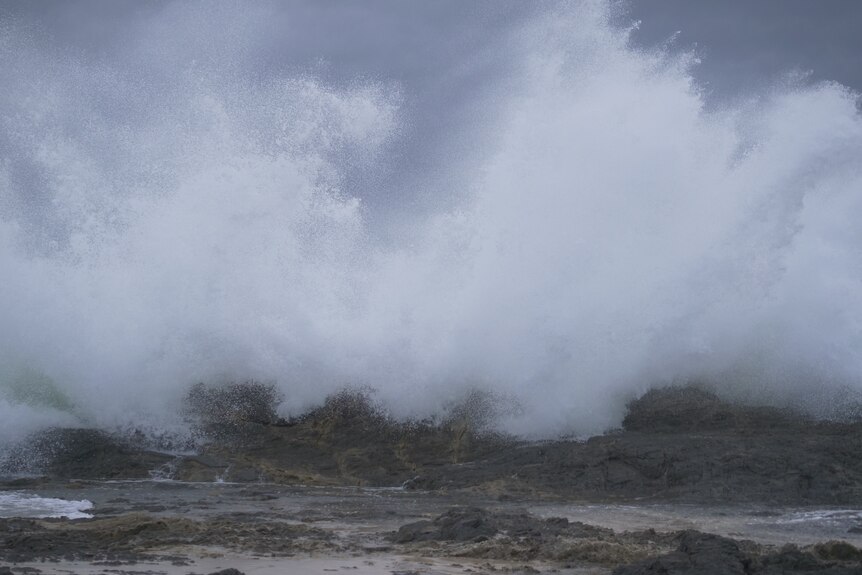 Seawater turns to spray as it smashes into rocks.