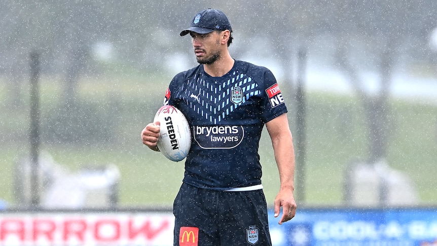 A man stands in the rain during a rugby league training session