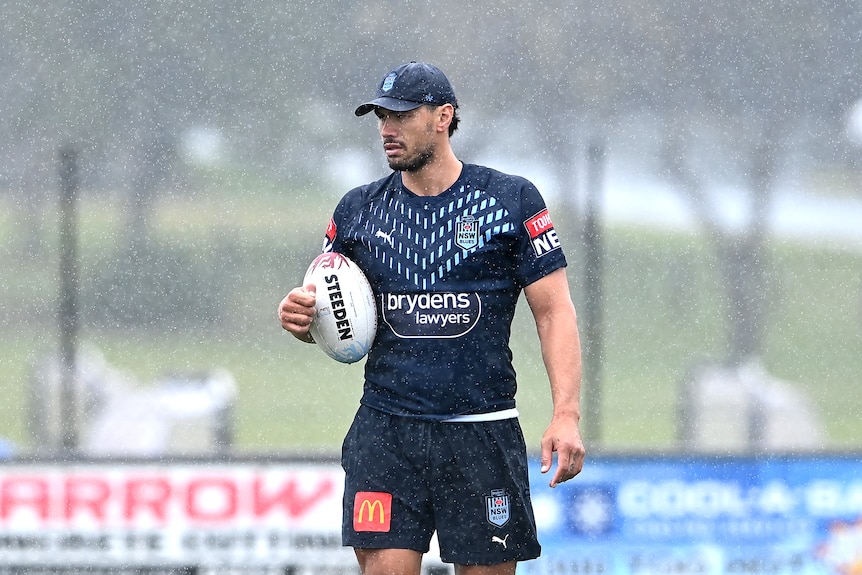 A man stands in the rain during a rugby league training session