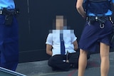 Student sits on the ground outside Arthur Phillip High in Sydney while surrounded by police.