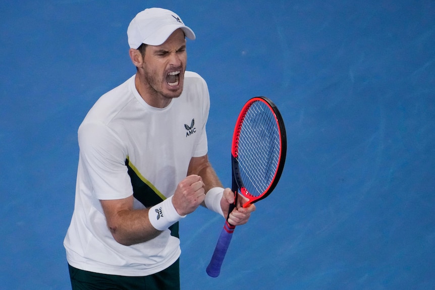 Andy Murray screams while clenching his fist and holding his tennis racquet.