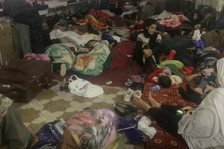 A group of people on blankets sit in a room.