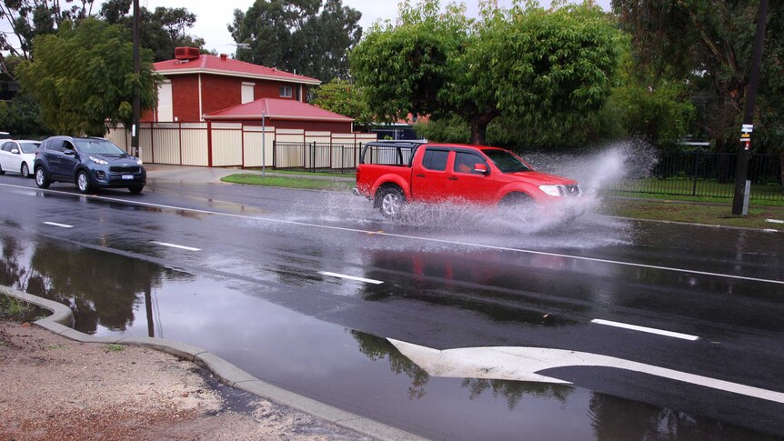 A utility drives through a large puddle on a wet August day in Perth.