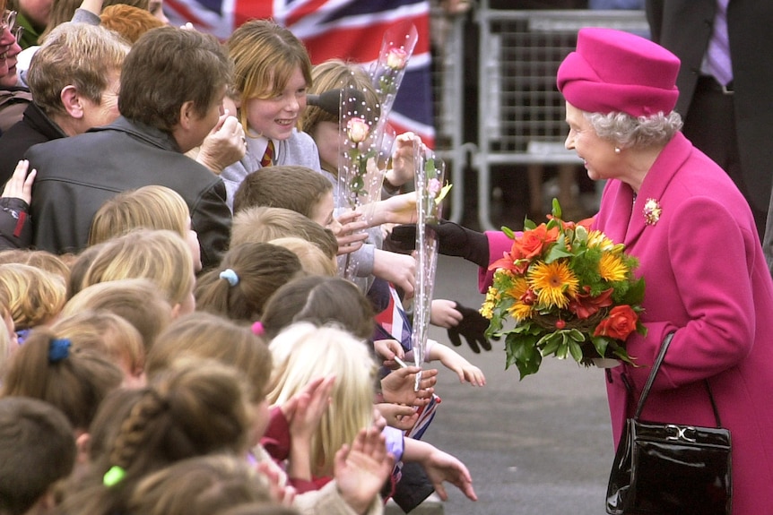 Queen Elizabeth is greeted by schoolchildren waving flowers