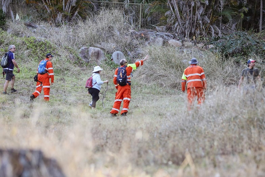 People in plain clothes and orange SES outfits in a line conducting a search