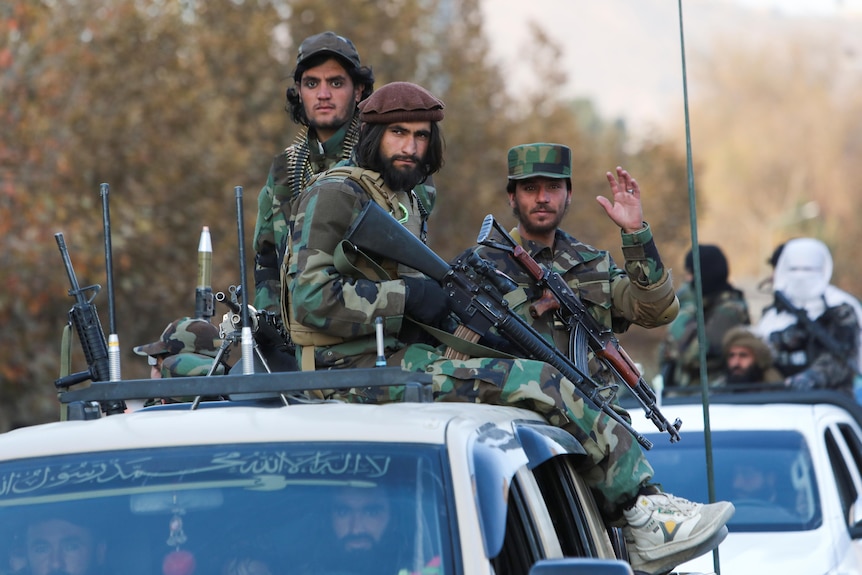 Taliban fighters sit armed atop a military vehicle during a Taliban parade in Kabul, November 2021.