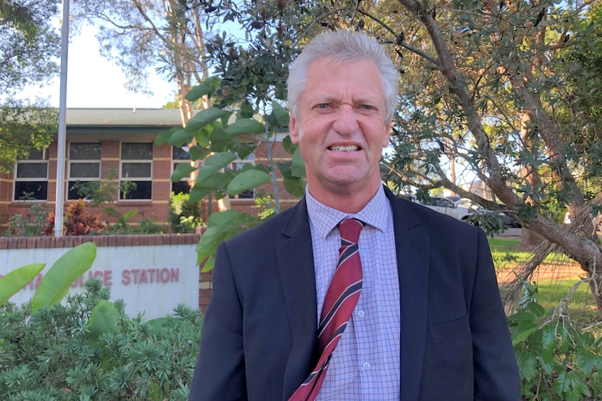 Man in suit in front of police station