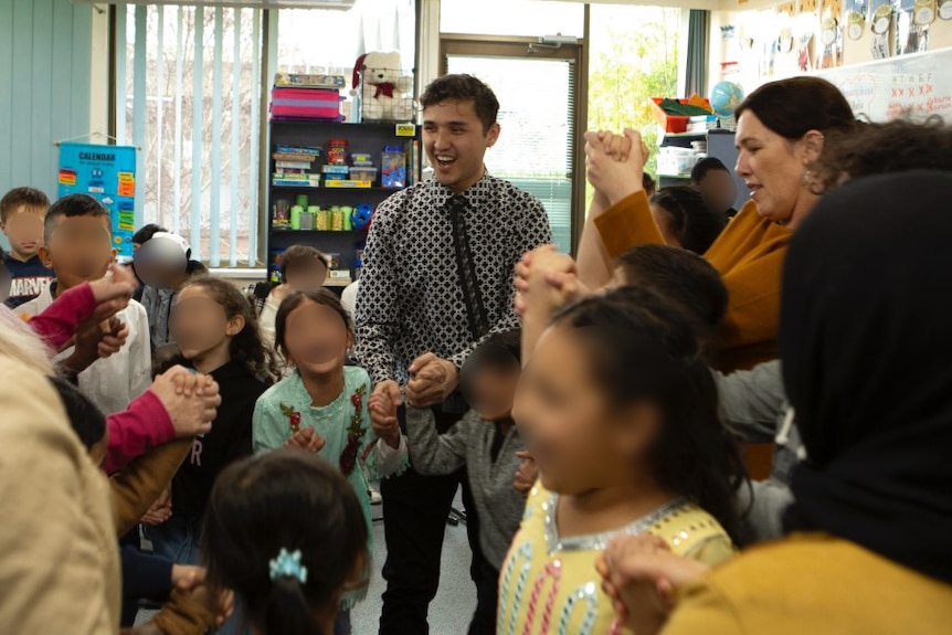 A man is surrounded by children in a classroom. 