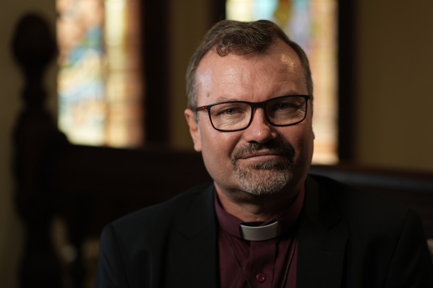 Reverend Gunton wearing clerical collar, wearing spectacles