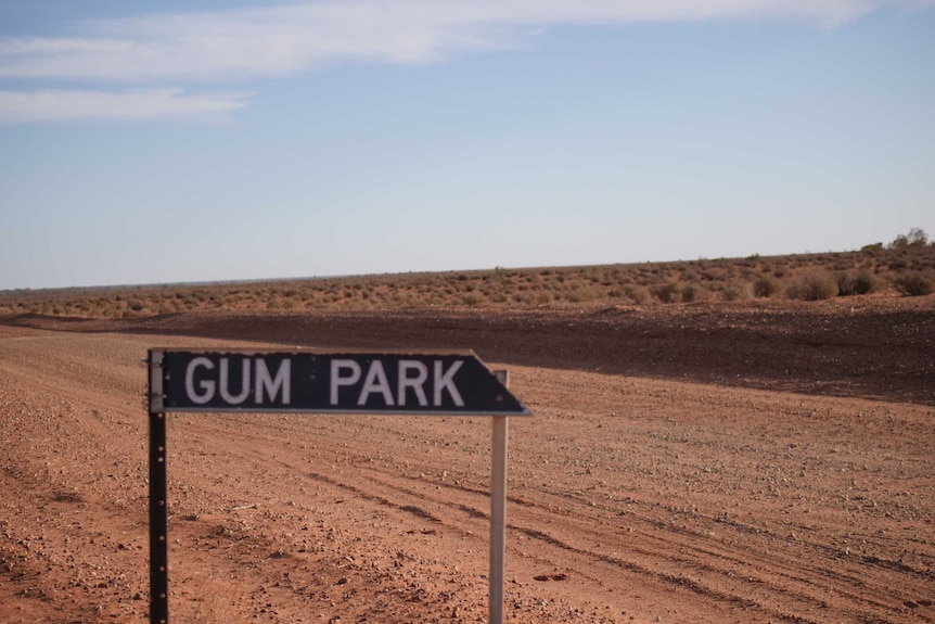 A sign that says "Gum Park," next to a red dusty outback road.