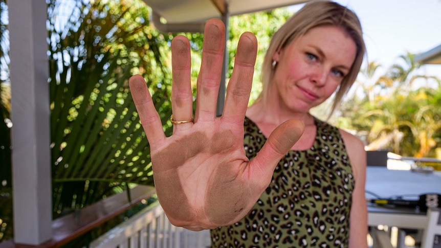 Moranbah resident shows her palm covered in dust after wiping it along a railing
