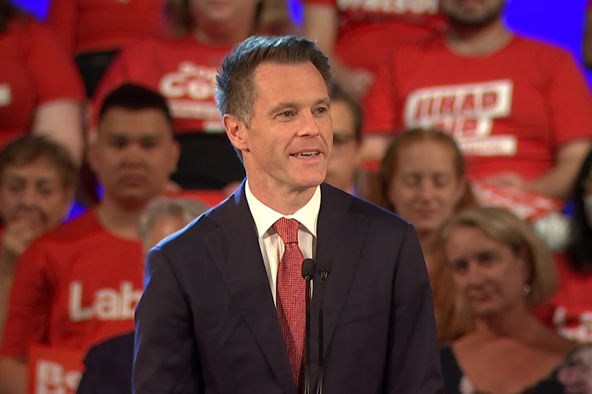 A man standing in front of a group of people who are clapping and cheering.