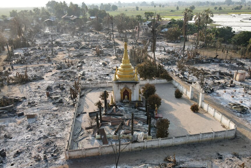 An aerieal view showing the spire of a gold pagoda standing but surrounded by ash of burned buildings 