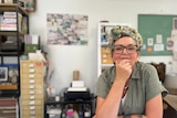 portrait of an artist women deep in thought at her art studio desk.