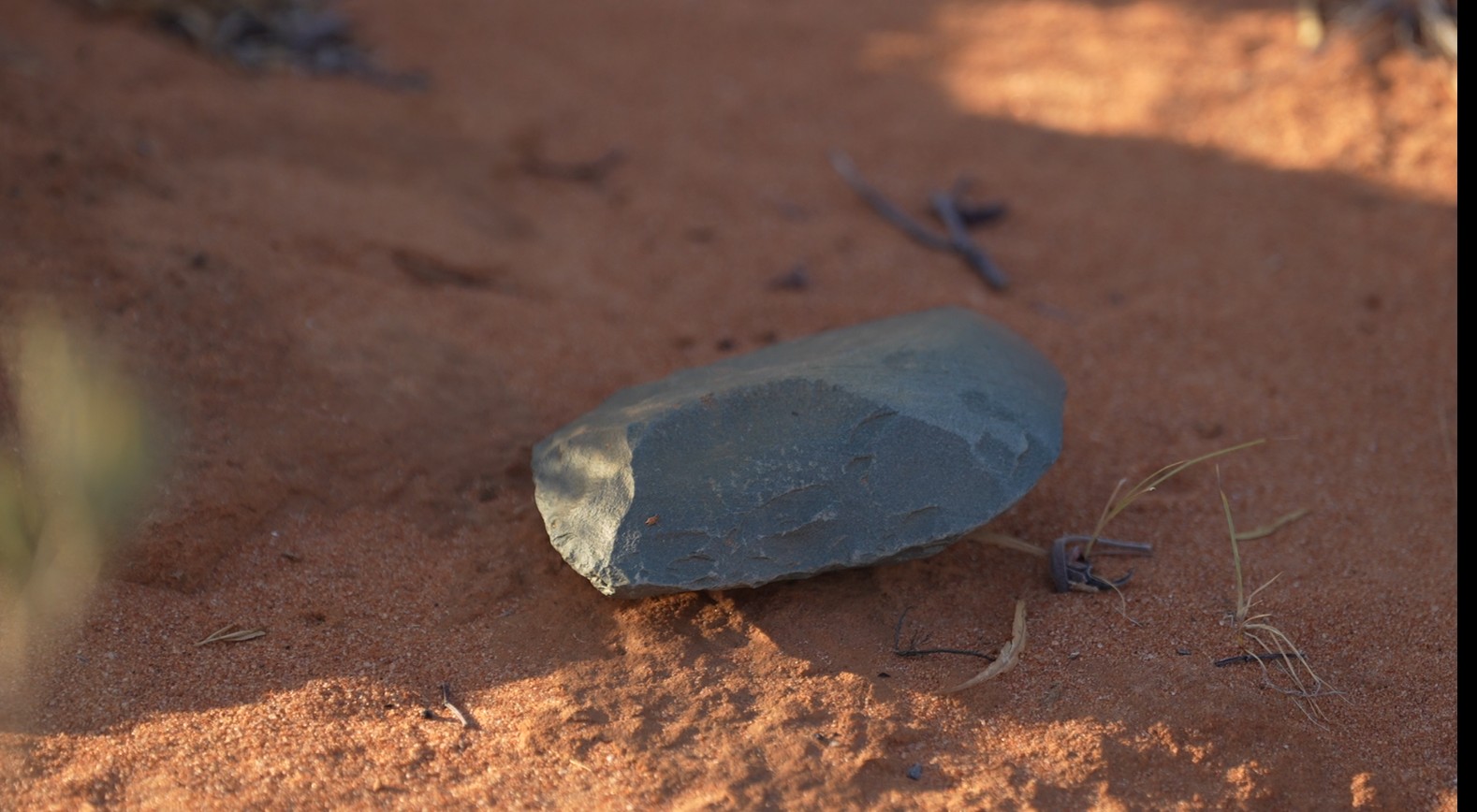 una piedra verde en el suelo del desierto a la sombra